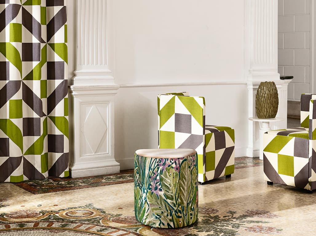 Das Bild zeigt einen Vorhang, Sesselstühle und Poufs mit Printmustern. Die eleganten Säulen und der Mosaikboden tragen zur harmonischen Stimmung bei, die durch die Muster der Möbel verstärkt wird.