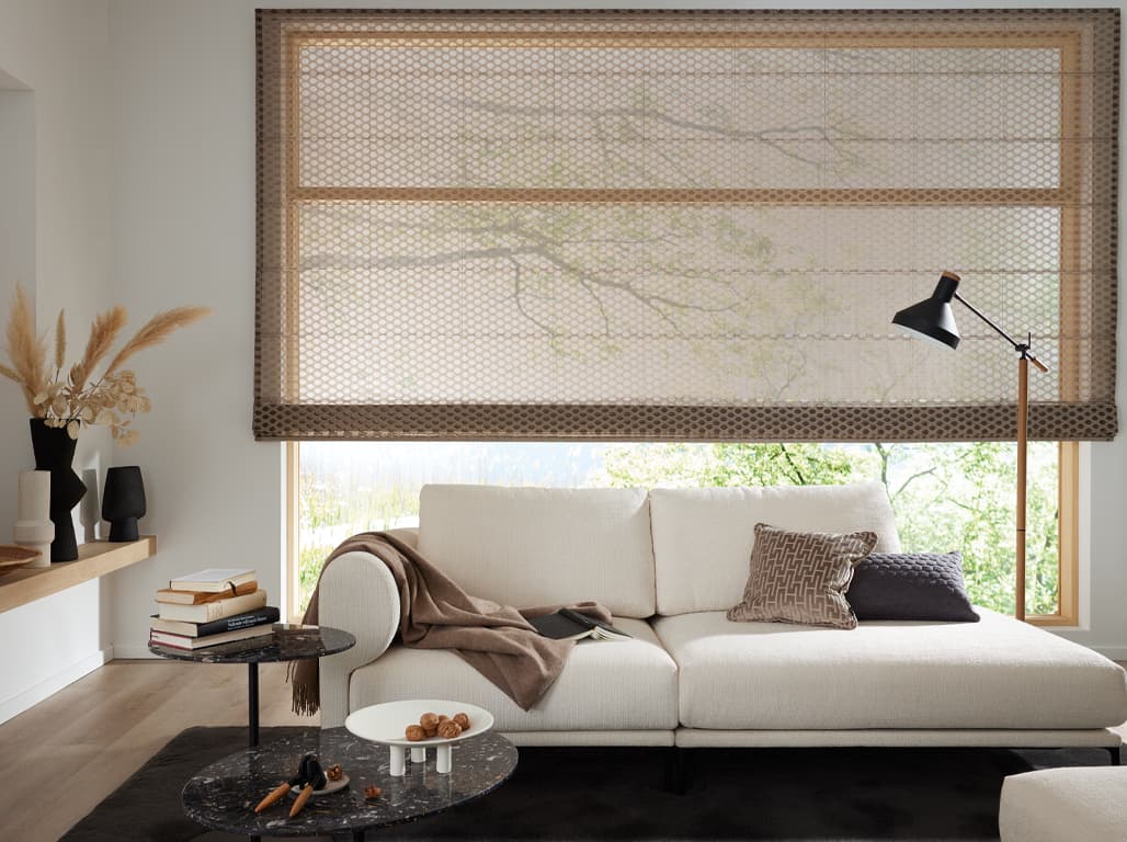 Faltrollo Circle in beige in einer Raumsituation mit weißem Sofa davor, auf einem schwarzen Teppich mit uwei kleinen Couchtischen und einer schwarzen Stehlampe rechts neben dem Sofa
