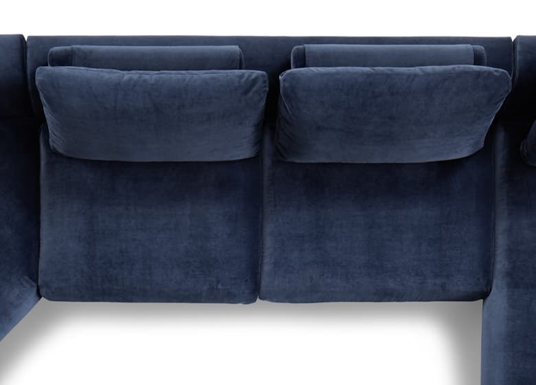 Sitzfläche eines blaeun Sofas von oben. Das Kissen ist geteilt, hinter ihm sind zwei Rückenkissen.