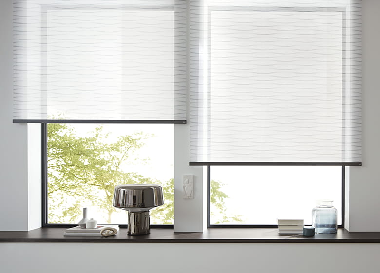 Fensterfront mit hellblauen Rollos und minimalistisch eingerichteter, moderner Fensterbank