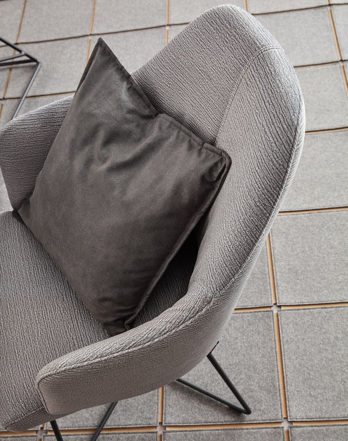 Detailaufnahme eines grauen Polsterstuhls mit dunkelgrauem Deko-Kissen