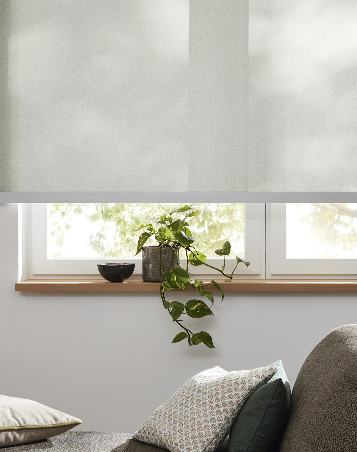 Hellgrünes Rollo mit silberner Schiene am Fenster
