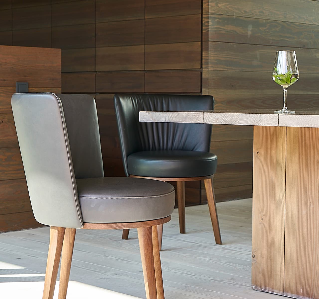 Polo Cocktail Stuhl in schwarz und grau an einem Tisch, auf dem ein leeres Weinglas steht