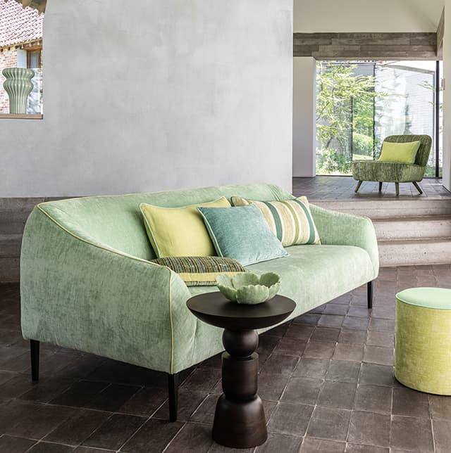Ein grünes Sofa mit gelb- und grüngemusterten Kissen.
