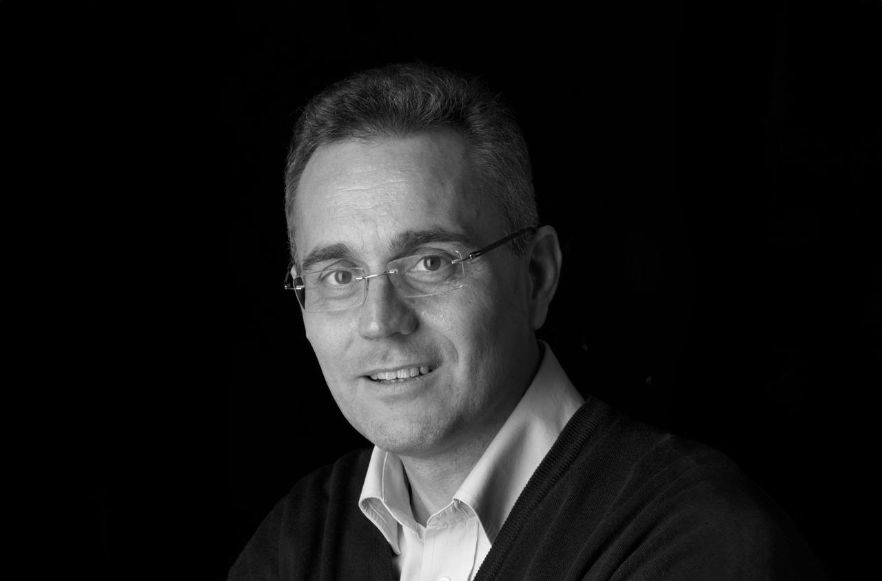 Portraitbild von einem Mann mit Rahmenloser Brille. Er schaut freundlich in die Kamera.